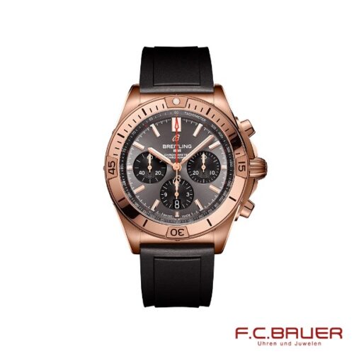 Die Breitling - Chronomat B01 42 rb0134101b1s1-9793934 ist eine Luxusarmbanduhr mit einer Lünette aus Roségold, einem schwarzen Zifferblatt und einem schwarzen Gummiarmband. Sie verfügt über drei Hilfszifferblätter und Stabindexe. Auf dem Zifferblatt ist die Marke „Breitling“ deutlich zu sehen, während in der unteren rechten Ecke das Logo und der Name „F.C. Bauer, Juwelier Bauer München“ zu sehen sind.